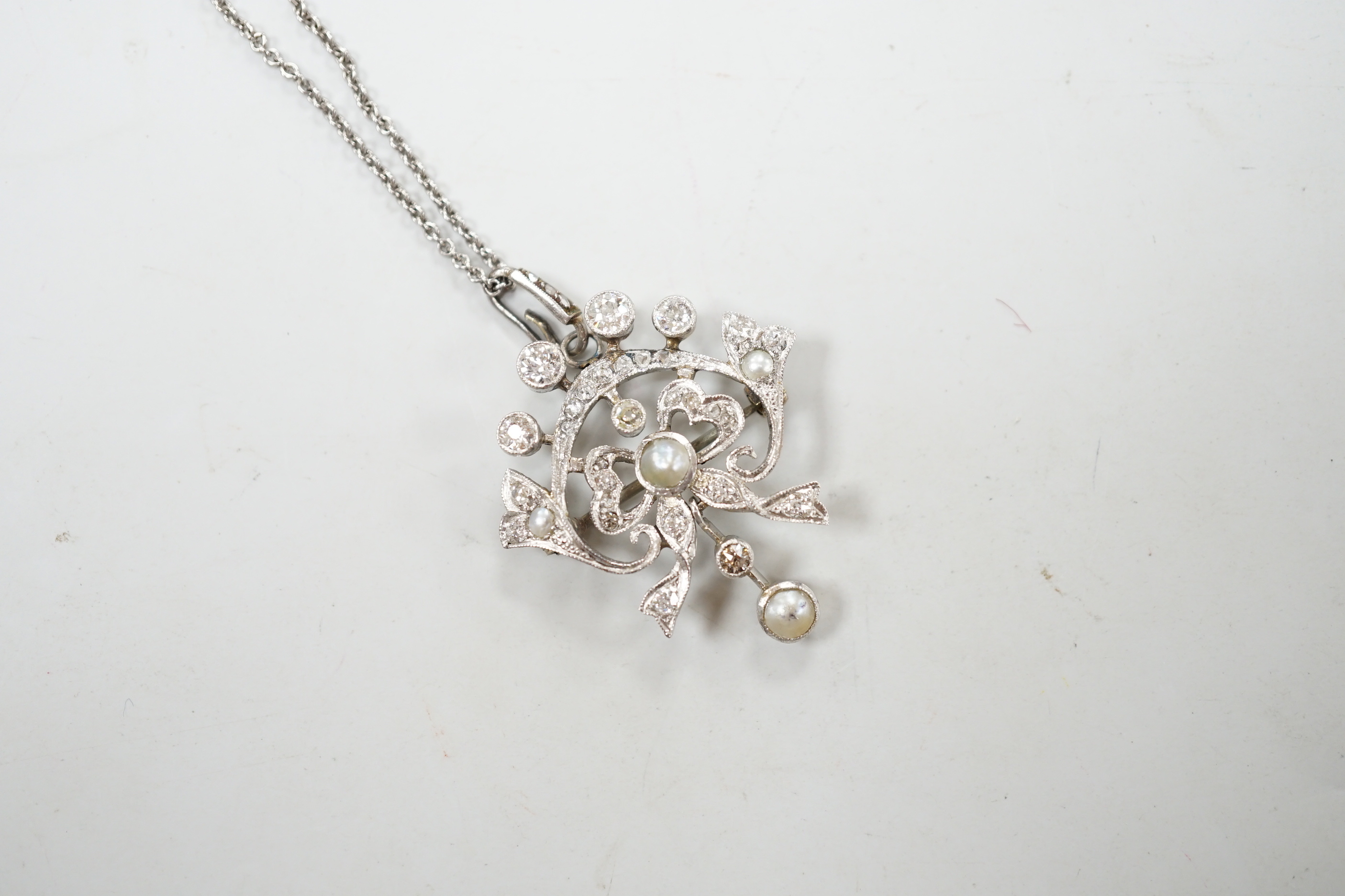 An early 20th century white metal, millegrain set diamond and split pearl cluster set drop pendant/brooch, overall 37mm, gross 5.8 grams, on a later sterling chain.